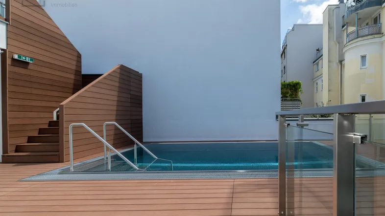 Moderne Dachterrasse mit integriertem Pool und Holzdeck, umgeben von städtischer Architektur.