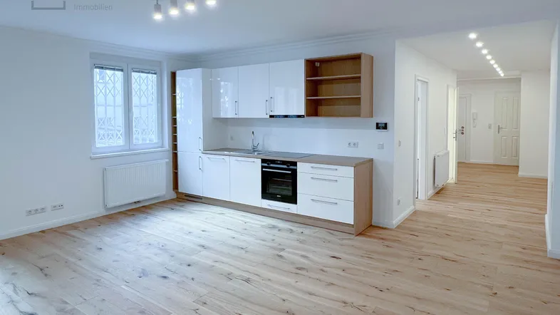 Helle Wohnküche mit moderner Einbauküche, Holzboden und Fenster.
