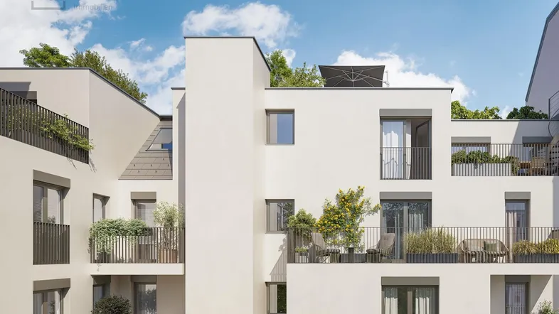 Moderne Fassade eines Wohngebäudes mit mehreren Balkonen und Terrassen unter blauem Himmel.