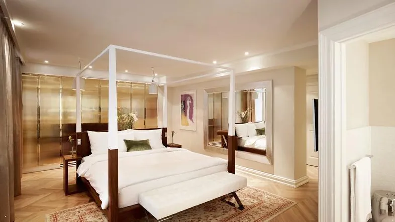 Elegantes Schlafzimmer mit Himmelbett, Parkettboden und integrierten Schränken, hell beleuchtet.