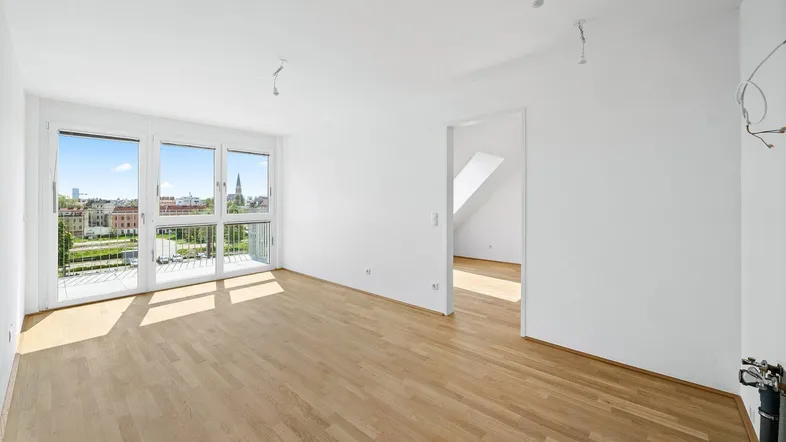 Helles Wohnzimmer mit Parkettboden, großen Fenstern und Zugang zu einem Balkon mit Stadtblick.