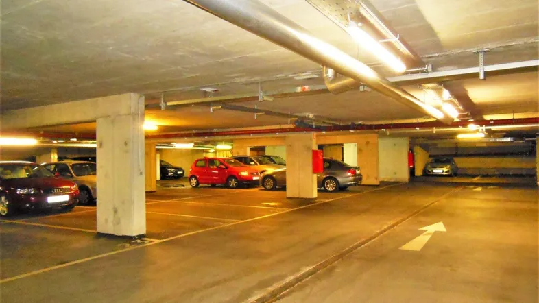 Geräumige Tiefgarage mit zahlreichen Stellplätzen, Betonstützen und funktionaler Beleuchtung.