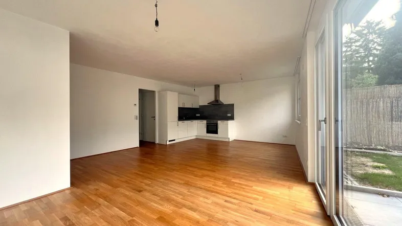 Heller offener Wohnbereich mit Holzboden und integrierter Küchenzeile, direktem Zugang zur Terrasse und Garten.
