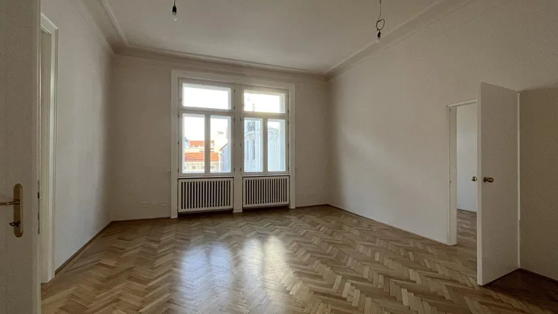 Geräumiges Zimmer mit Fischgrätparkett, hohen Decken und Stuckverzierungen, bereit zur individuellen Gestaltung.