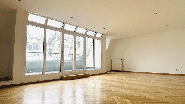 Helles Wohnzimmer mit Fischgrätparkett und großen Fenstern, die viel Tageslicht hereinlassen.