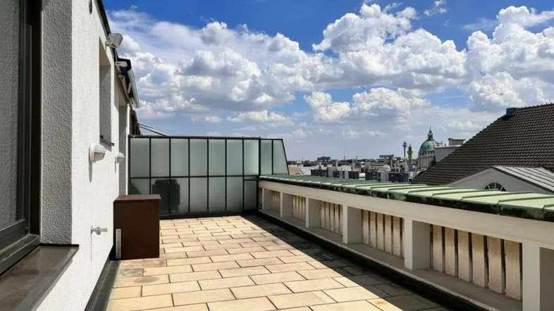 Geräumige Dachterrasse mit Fliesenboden, Glasstruktur und weitem Blick über die Stadt.