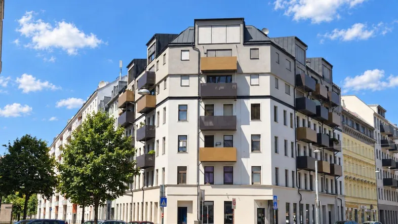 Modernes Mehrfamilienhaus mit Balkonen und großen Fenstern an einer städtischen Straße.