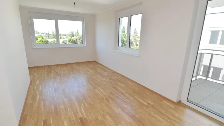 Helles Zimmer mit Parkettboden und Zugang zu einem Balkon, ideal als Schlaf- oder Wohnbereich.