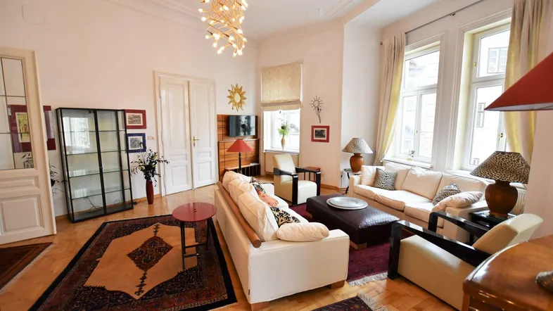 Helles Wohnzimmer mit Fischgrätparkett, Stuckdecke und bequemen Sofas in einem Altbau.