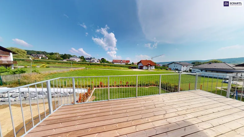 Geräumige Holzterrasse mit Metallgeländer und weitem Blick ins Grüne und auf die umliegende Landschaft.