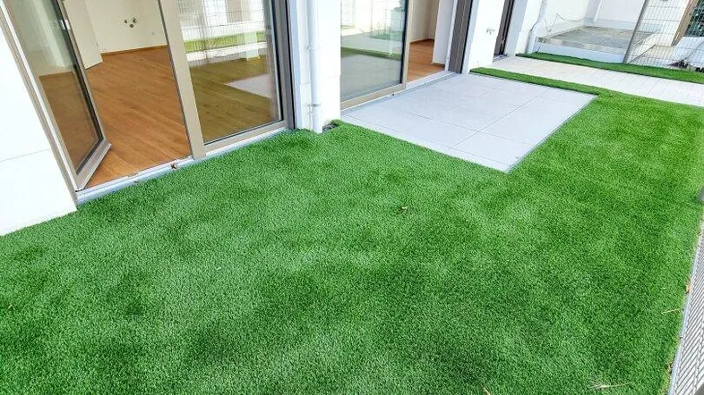 Kleiner privater Gartenbereich mit Kunstrasen und Zugang zu den Innenräumen über Glasschiebetüren.