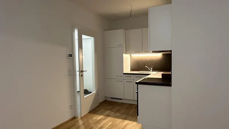 Helle Küche mit weißen Schränken, dunkler Arbeitsplatte und Holzfußboden.