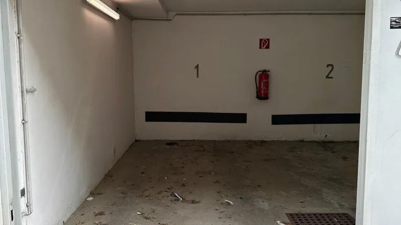 Leere Tiefgarage mit Betonboden und weiß gestrichenen Wänden, bereit zur Nutzung.