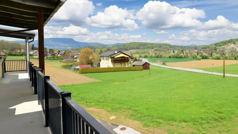 Weitläufiger Ausblick vom Balkon auf die grüne Landschaft und ferne Berge.