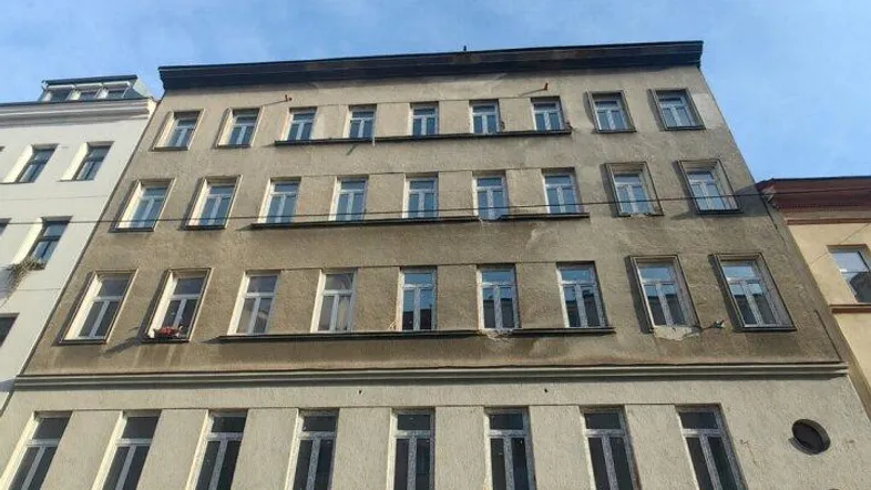 Altes Gebäude mit mehreren Stockwerken und vielen Fenstern an der Fassade unter blauem Himmel.