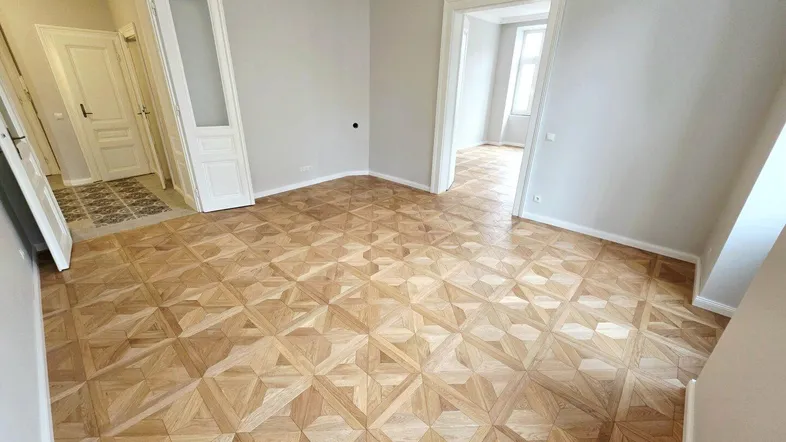 Geräumiges Zimmer mit elegantem Parkettboden und hohen Decken, bereit zur Einrichtung.