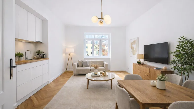 Helles, offenes Wohn-Esszimmer mit integrierter Küchenzeile und modernem Fischgrätparkettboden.