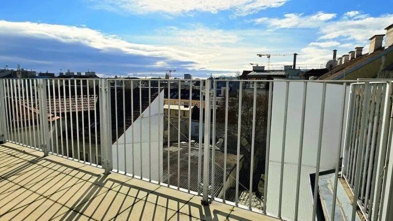 Sonnige Dachterrasse mit Fliesenboden und weitem Blick über die Stadt.