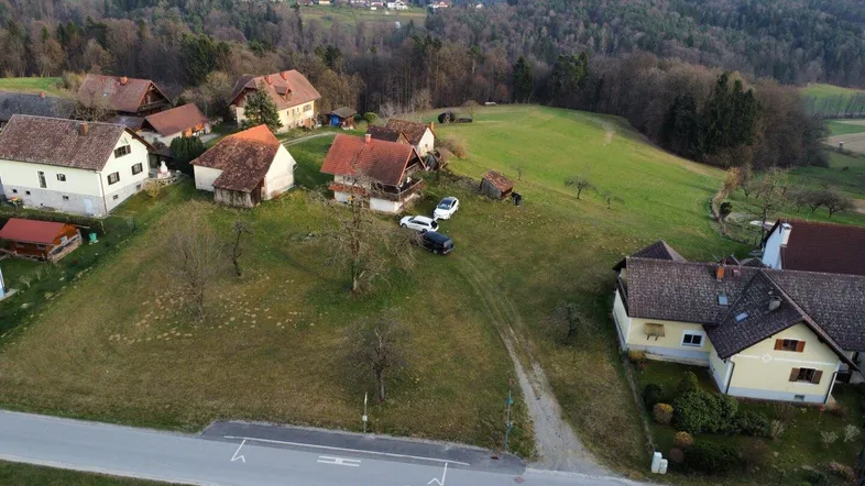 Luftaufnahme eines ländlichen Wohngebiets mit mehreren Häusern und grünen Hügeln im Hintergrund.