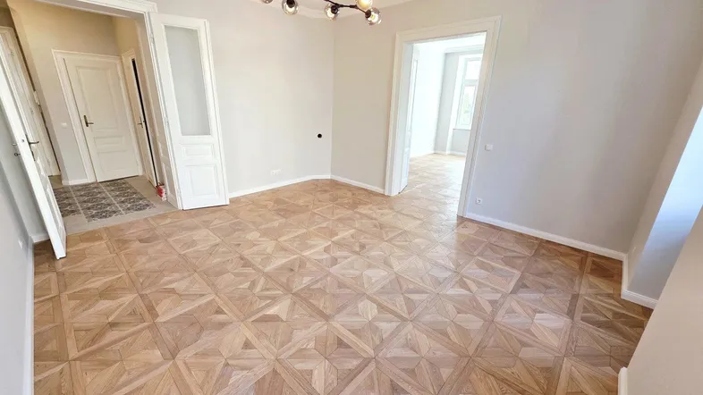 Geräumiges Zimmer mit elegantem Fischgrätparkett und hohen Decken, bereit zur individuellen Gestaltung.