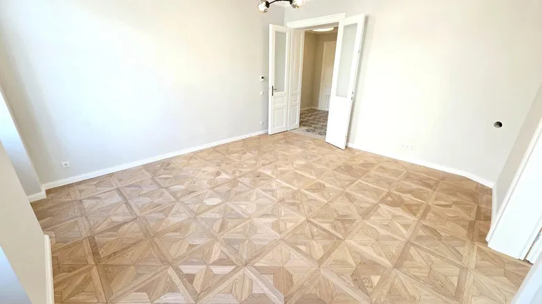 Helles Zimmer mit elegantem Parkettboden und hohen Decken, bereit zur individuellen Gestaltung.