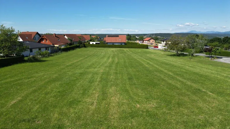 Weitläufiges grünes Grundstück mit umliegenden Häusern und Blick auf die hügelige Landschaft.
