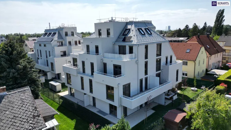 Moderne weiße Mehrfamilienhäuser mit Flachdächern und Balkonen in einer grünen Umgebung.