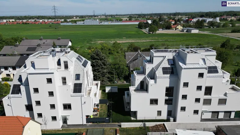 Luftaufnahme von zwei modernen Wohngebäuden mit Photovoltaikanlagen und grüner Umgebung.