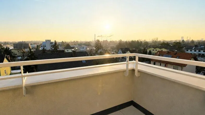 Sonnenuntergang über der Stadt von einem modernen Balkon mit Fliesenboden und weitem Blick.