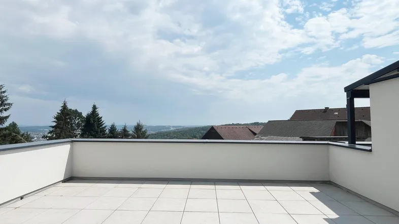 Weitläufige Terrasse mit Fliesenboden und weitem Blick über die umliegende Landschaft.