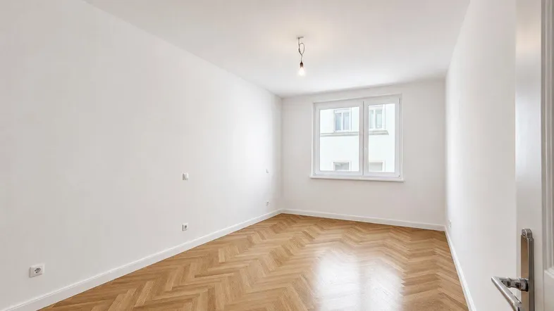 Heller, leerer Raum mit Fischgrätparkett und weiß gestrichenen Wänden, bereit zum Einzug.