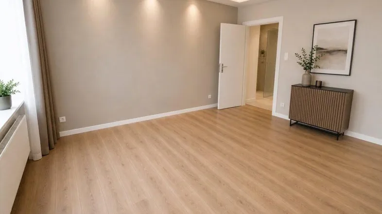 Helles Zimmer mit modernem Laminatboden, indirekter Beleuchtung und Zugang zu einem Badezimmer.