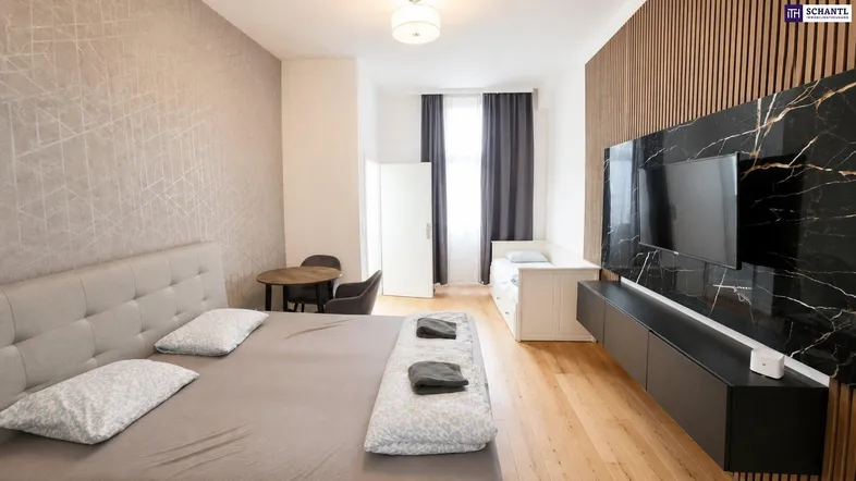 Modernes Schlafzimmer mit Holzboden, einem Doppelbett und einem stilvollen TV-Bereich mit Marmoroptik.