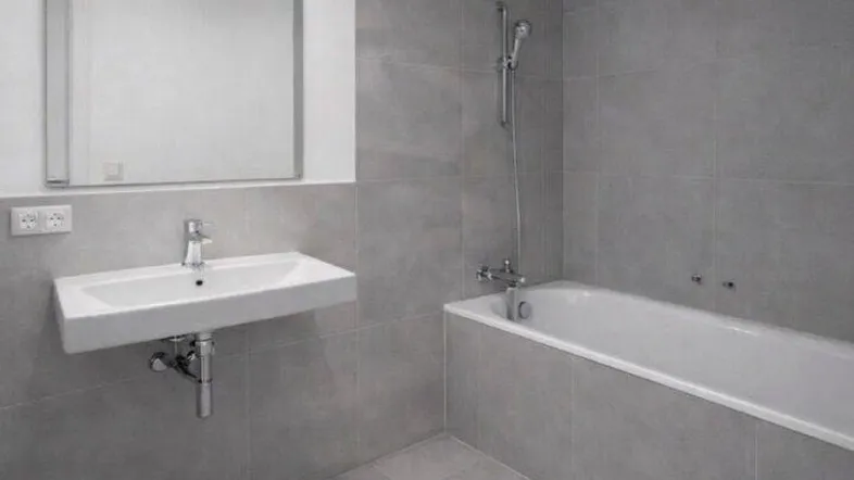 Modernes Badezimmer mit grauen Fliesen, Badewanne und einem einzelnen Waschbecken.