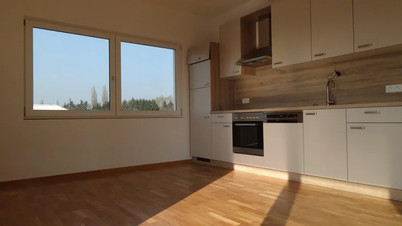 Helle Küche mit Einbauküche, Holzoptik-Arbeitsplatte und großem Fenster mit Blick ins Grüne.