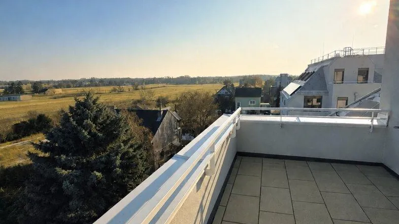 Geräumige Dachterrasse mit Fliesenboden und weitem Blick über die Landschaft bei Sonnenuntergang.