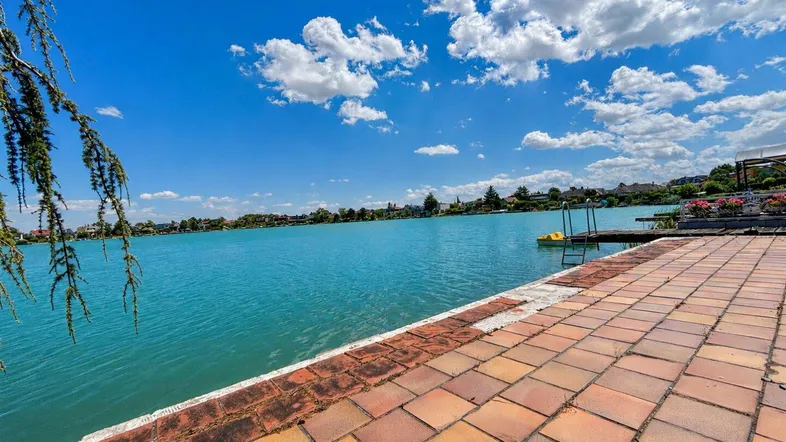Große geflieste Terrasse direkt am Seeufer mit weitem Blick über das türkisfarbene Wasser.