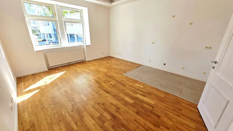 Helles Zimmer mit Parkettboden und großen Fenstern, bereit zur individuellen Gestaltung.