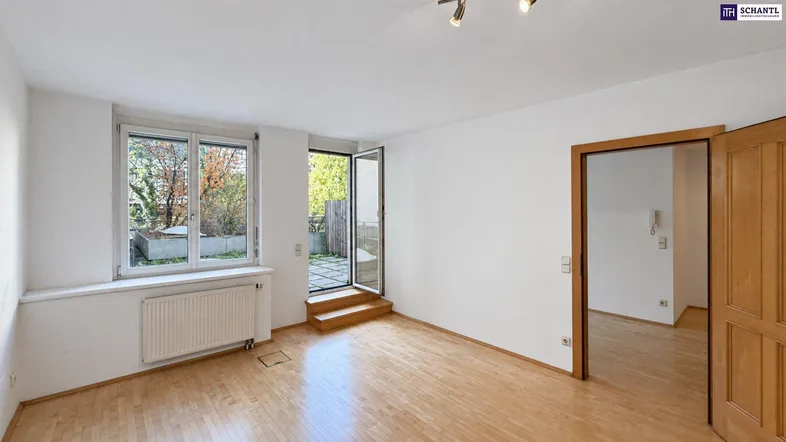 Helles Wohnzimmer mit Holzboden und Zugang zu einer kleinen Terrasse oder einem Gartenbereich.