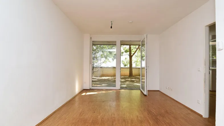 Helles Wohnzimmer mit Holzboden und Zugang zu einer Außenterrasse, ideal für entspannte Stunden.