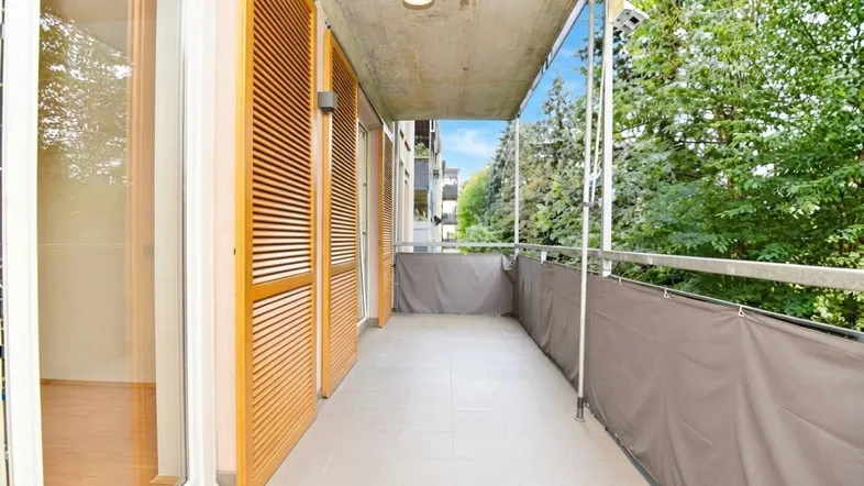 Langer Balkon mit Holzelementen und Blick ins Grüne, ideal zum Entspannen im Freien.