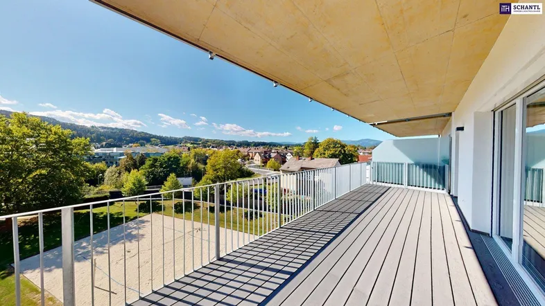 Große Terrasse mit Holzboden, Metallgeländer und weitem Blick auf die grüne Umgebung und Berge.