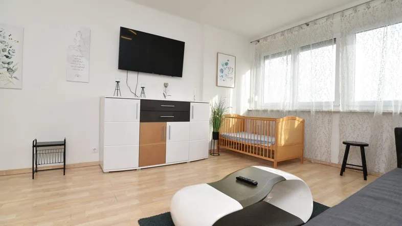 Helles Wohnzimmer mit modernem Sideboard, Fernseher und Laminatboden.