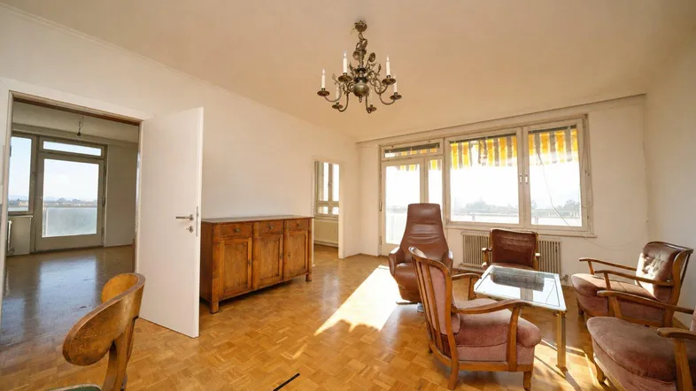 Helles Wohnzimmer mit Parkettboden, Kronleuchter und Zugang zu einem Balkon mit Weitblick.