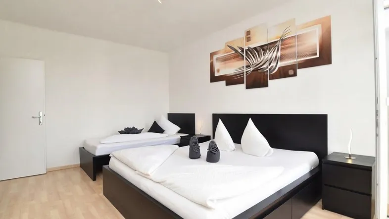 Helles Schlafzimmer mit zwei Betten, Nachttischen und dekorativem Wandbild.