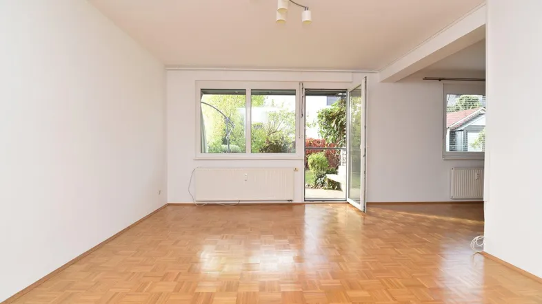 Helles Wohnzimmer mit Parkettboden und Zugang zur Terrasse oder zum Garten.