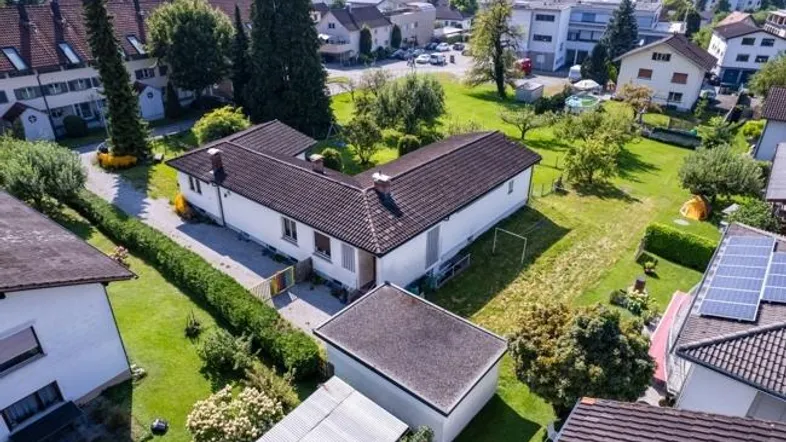 Luftaufnahme eines Einfamilienhauses mit großem Garten und umliegender Wohnbebauung.