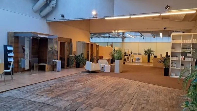 Großer, offener Ausstellungsraum mit Holzboden, Oberlichtern und verschiedenen Wellness-Produkten.