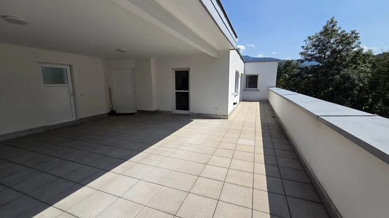 Geräumige, sonnige Terrasse mit Fliesenboden und Blick auf die umliegende Natur.