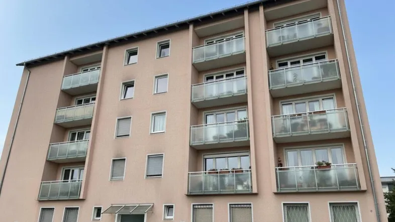 Mehrstöckiges Wohngebäude mit zahlreichen Balkonen und einer hellen Fassade unter klarem Himmel.